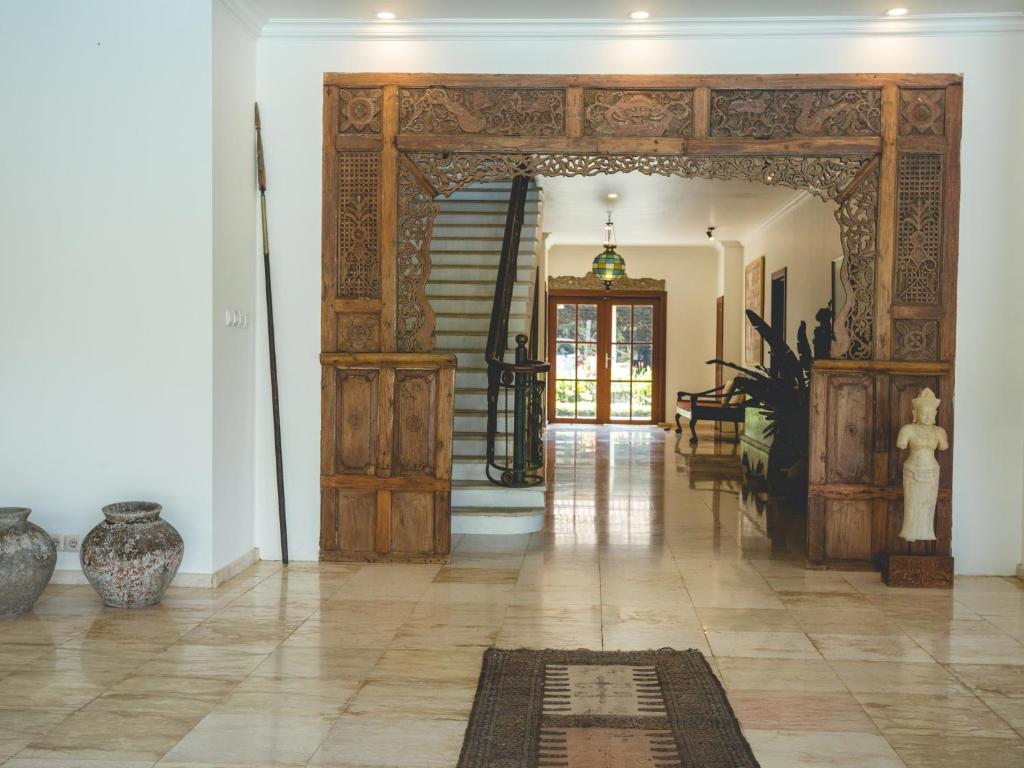 Decorative wooden archway in a well-lit room with a staircase and furniture.